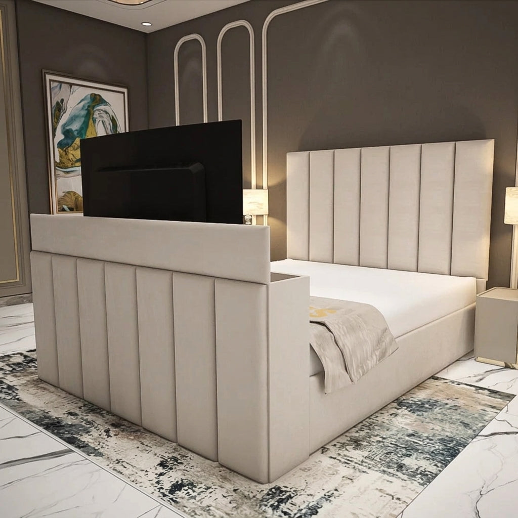 A modern upholstered bed with a tall channel-tufted headboard and matching footboard, shown in a styled bedroom setting with a TV mounted on the back of the headboard, bedside lamps, marble flooring, and a patterned rug.