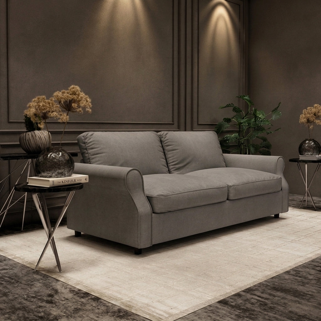 A modern two-seater sofa in textured gray fabric, styled in a contemporary living room setting with a cream rug, side tables, dried flowers, and a potted plant against a dark paneled wall.