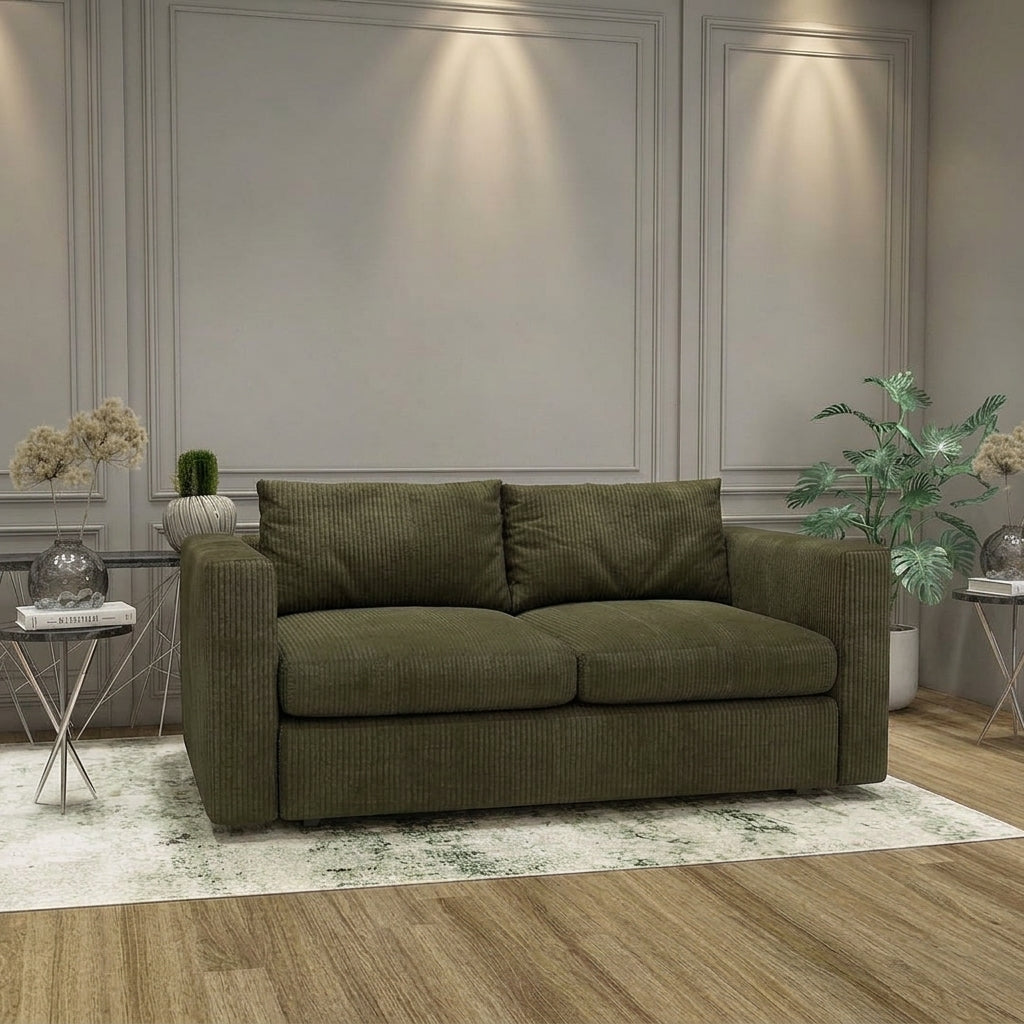 An olive green corduroy loveseat sofa placed in a styled living room setting with a light patterned rug, side tables, plants, and wall paneling.